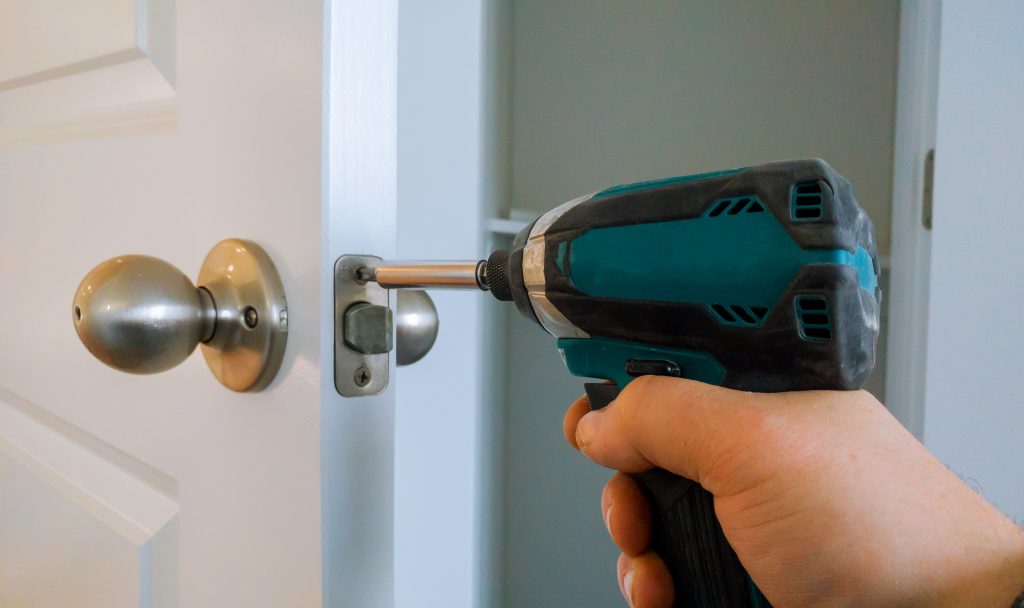 Hands repairing a door lock with a screwdriver